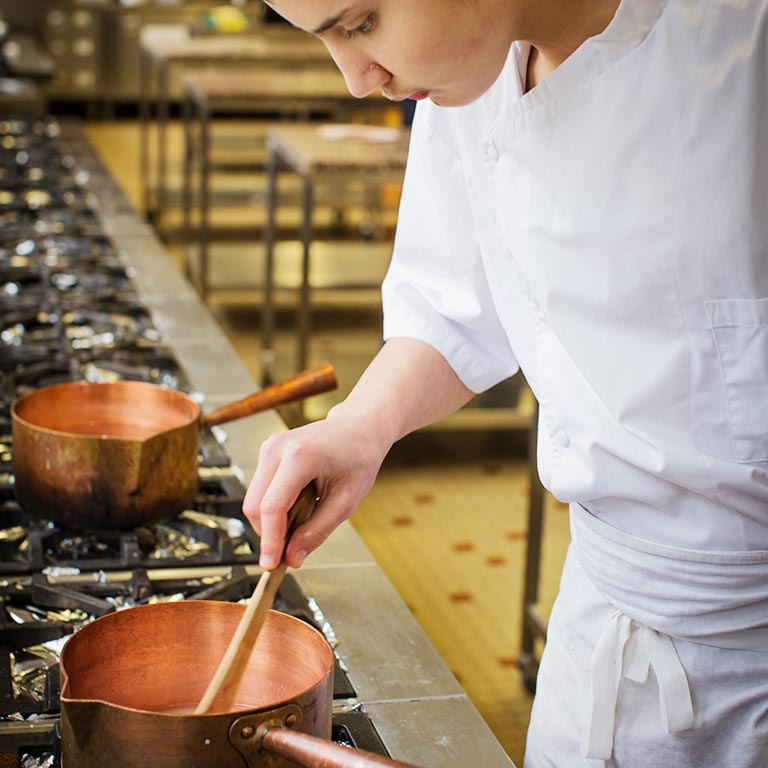Un jeune apprenti prépare un caramel dans le laboratoire de pâtisserie de l'École des Métiers