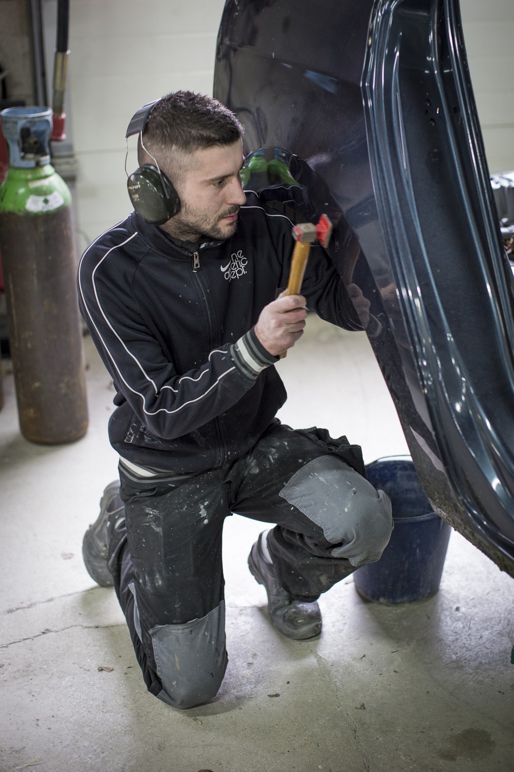 Un apprenti carrossier réalise une réparation sur une carrosserie dans un atelier de l'EDM.